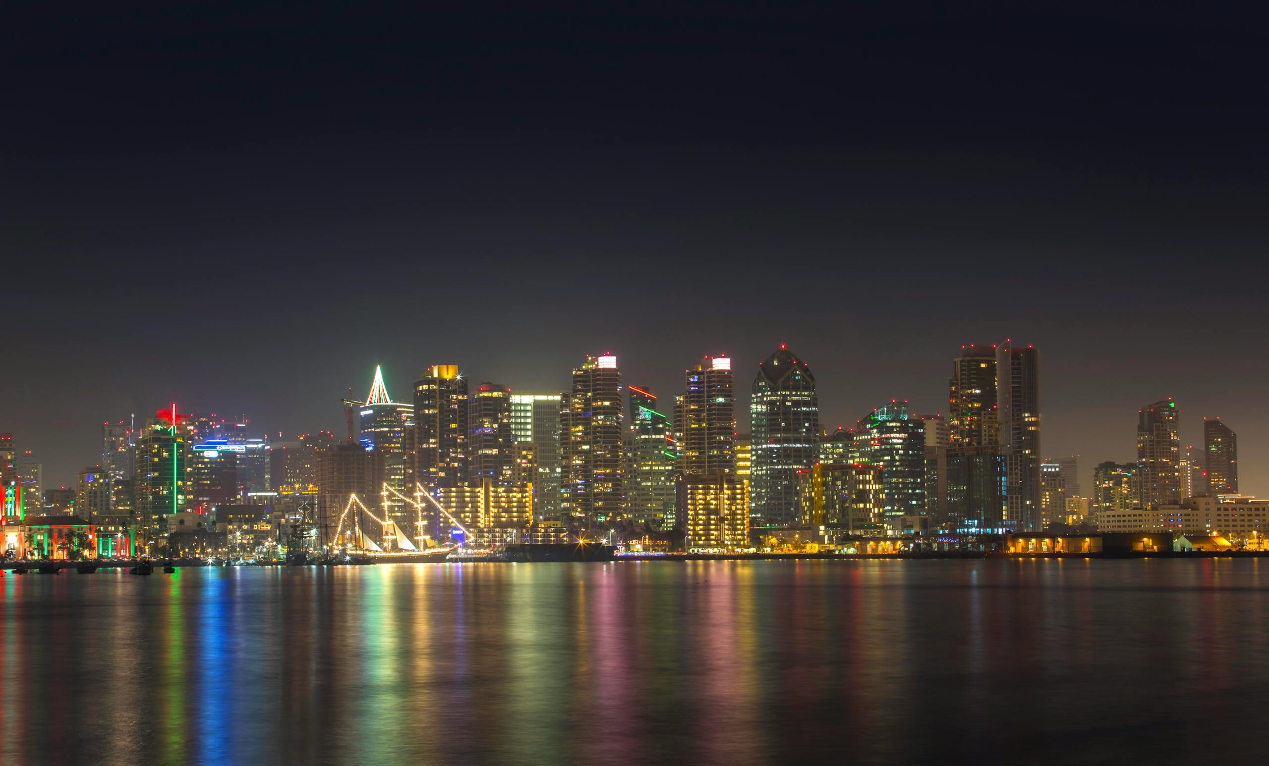 A serene night view of San Diego's illuminated skyline reflecting on calm water.